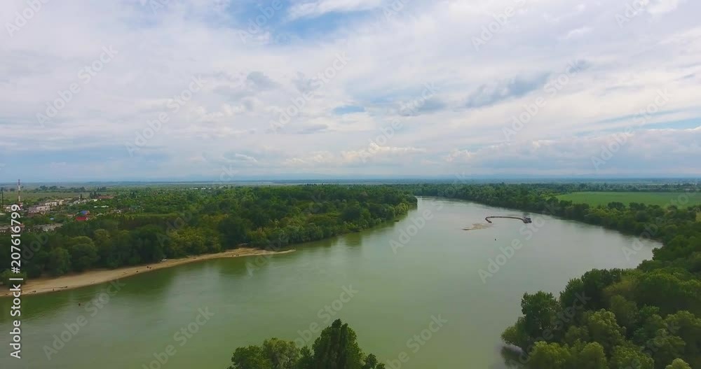 Aerial flight over beautiful bend of river with fishermen sitting in boats and forest belt along river under boundless blue sky with white clouds Aerial flight over beautiful bend of river with fishermen sitting in boats and forest belt along river under boundless blue sky with white clouds