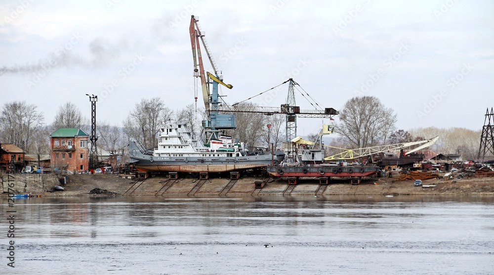Maintenance ships / IRKUTSK, RUSSIA - April 11, 2018: Viewed to cargo shipyard of Irkutsk city along Angara river, Siberian area. Lots of ships park for maintenance and transferring Maintenance ships / IRKUTSK, RUSSIA - April 11, 2018: Viewed to cargo shipyard of Irkutsk city along Angara river, Siberian area. Lots of ships park for maintenance and transferring