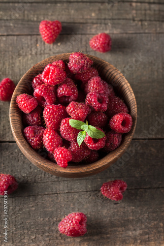 Ripe fresh sweet raspberries in a wooden bowl on wooden table background.