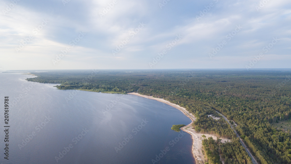 Aerial view of winding road along coastline through lush green forest Aerial view of winding road along coastline through lush green forest