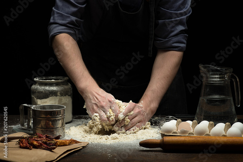 Hands are mixing a dough on wooden table