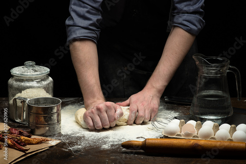 Hands are kneading the dough on wooden table