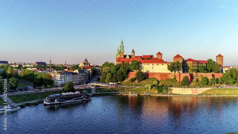 Krakow, Poland. Wawel royal Castle and Cathedral, Vistula River, park, harbor, walking people and a flying seagull. Cracow old city in the background. Aerial 4K reveal video at sunset in spring Krakow, Poland. Wawel royal Castle and Cathedral, Vistula River, park, harbor, walking people and a flying seagull. Cracow old city in the background. Aerial 4K reveal video at sunset in spring