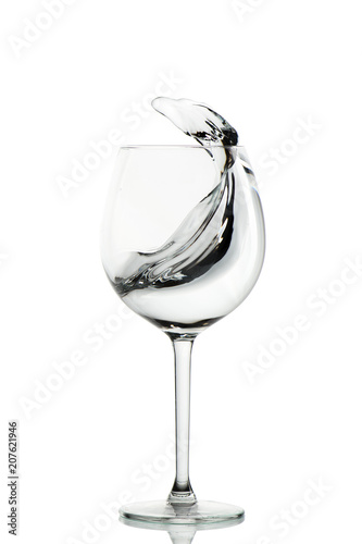 Clear water splashing in the wine glass. vertical isolated