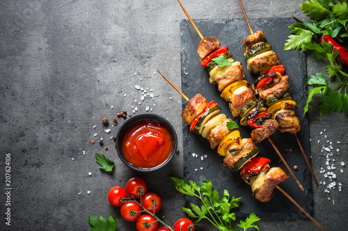 Grilled shish kebab with vegetables on black.