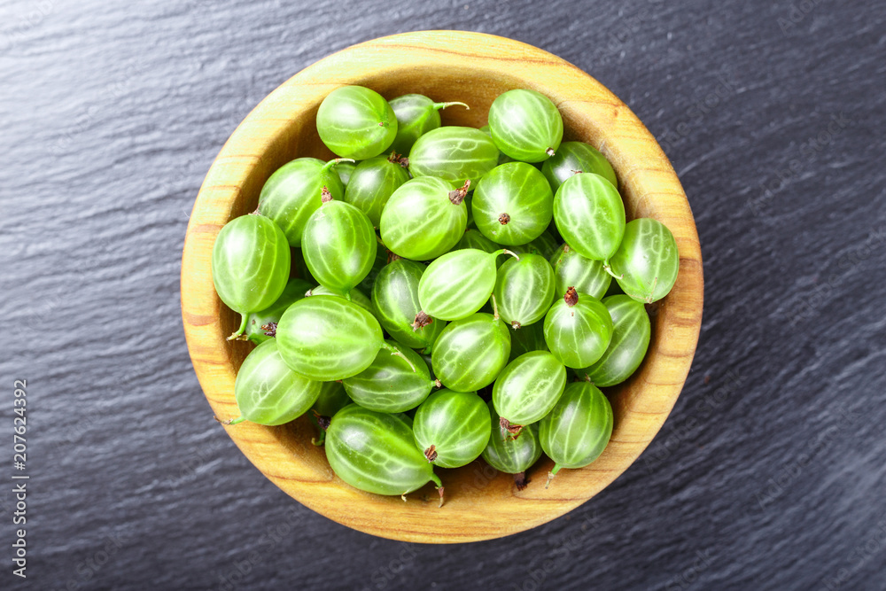 Ripe gooseberry in a  plate, place for text, top view