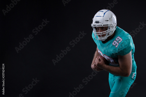 Portrait of American football player holding a ball in both his arms. Copy space. Rugby photo