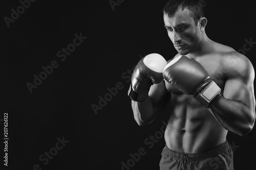 Muscular man in boxing gloves at black background © Prostock-studio
