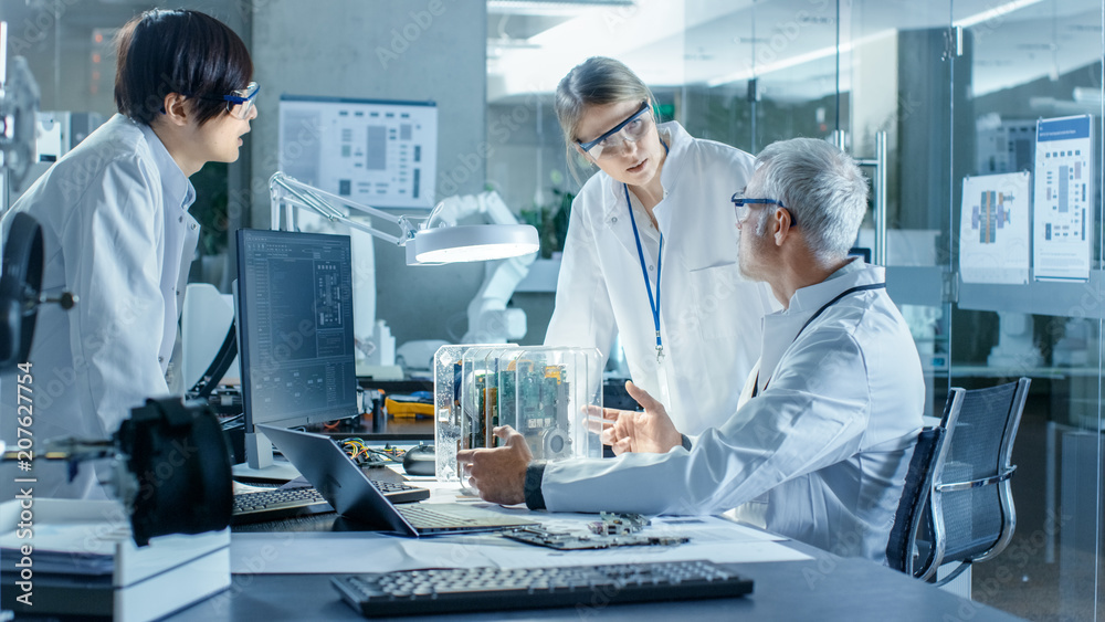 Team of Scientists Choose Between Printed Circuit Board to Work With. In The Background Technologically Advanced Scientific Research Center.