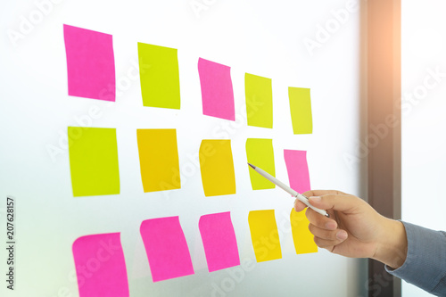 Businessman hands are pointing to empty sticky notes on glass wall at Meeting Conference Discussion Corporate.