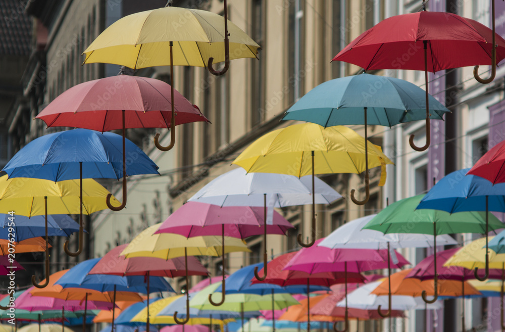 colorful umbrellas hang on the background of the old city in the lviv