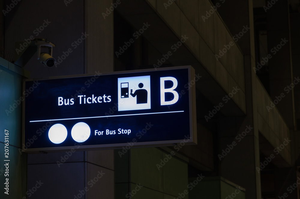 bus tickets sign billboard at airport or train station at night, transportation and travel concept