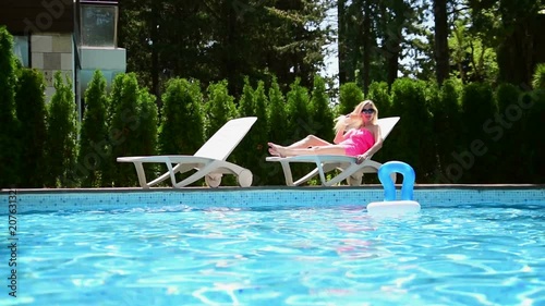The young woman sunbathes near the water pool
