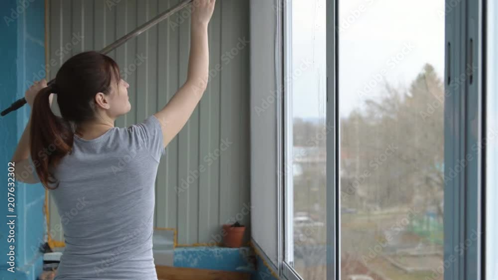 Young woman washing windows with rubber mop. Young woman washing windows with rubber mop.