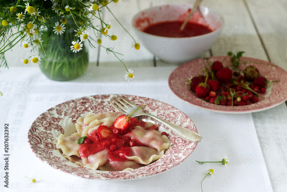 A hearty homemade breakfast or lunch - dumpling or vareniki with strawberries and strawberry sauce. Rustic style. A hearty homemade breakfast or lunch - dumpling or vareniki with strawberries and strawberry sauce. Rustic style.