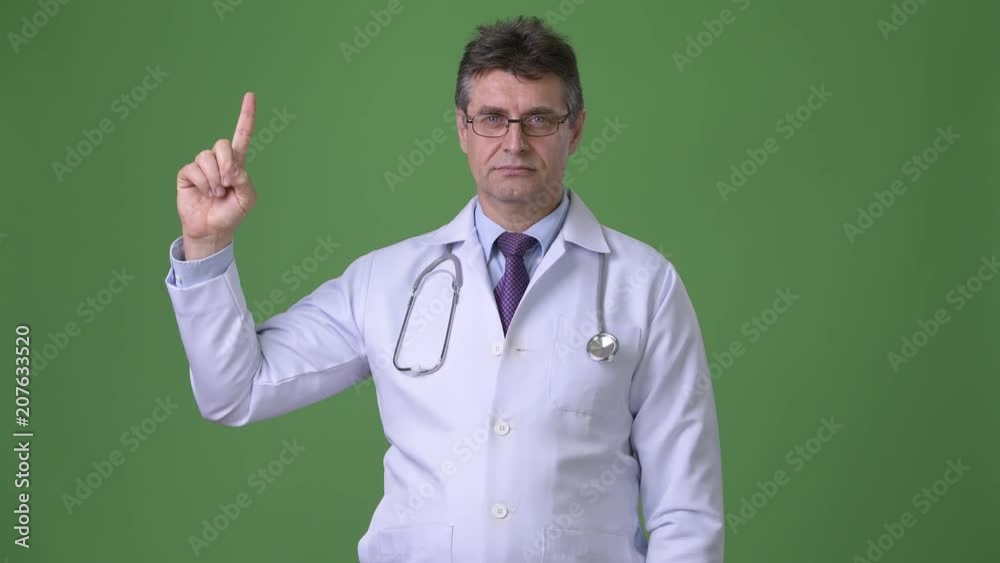 Mature handsome man doctor against green background