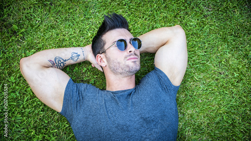 Good looking, fit male model relaxing lying on the grass, looking at camera, photographed right from above © theartofphoto