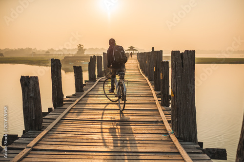 Man cycling on a wooden bridge at sunrise