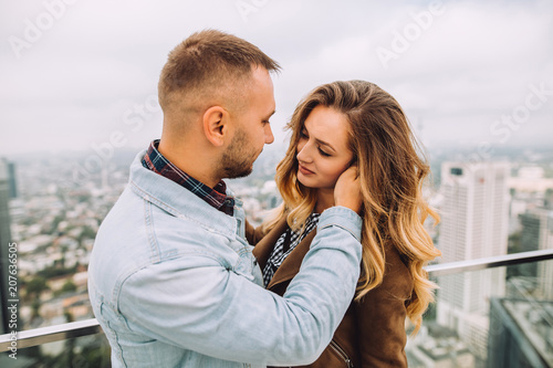 Young man looks into the eyes of his beloved girl in a skyscraper.In the background is the beautiful city of Frankfurt from a height.