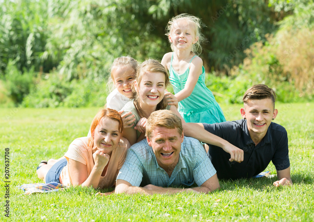 Smiling man and woman with kids lying in park