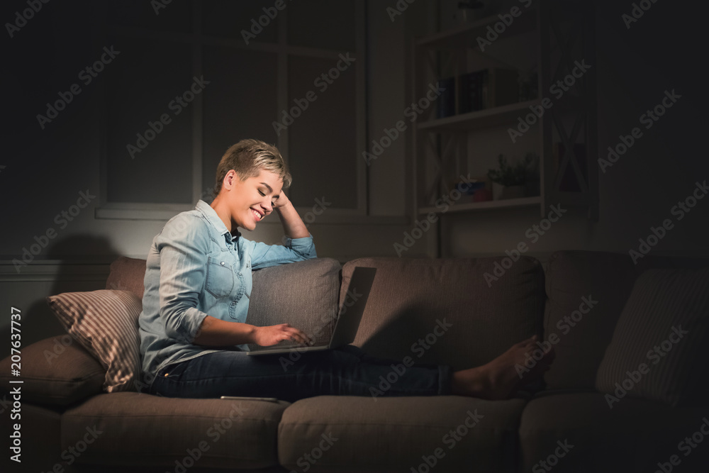 Happy woman with laptop at dark home office copy space