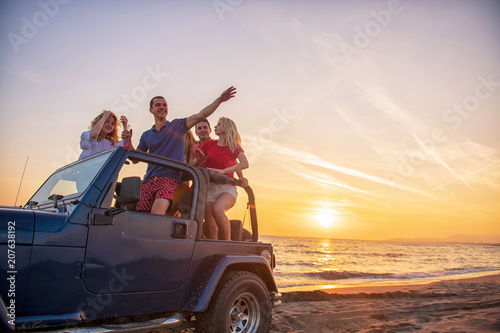Young people having fun in convertible car at the beach at sunset. © blicsejo