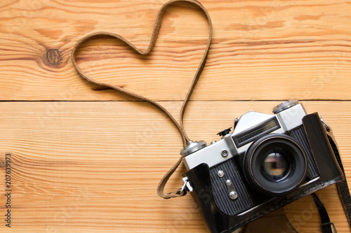 Old vintage camera on a wooden table. Heart shape
