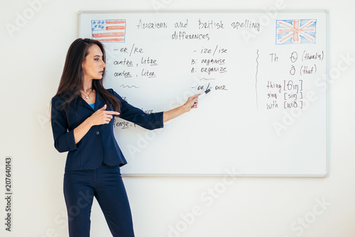 Teacher explaining differences between American and British spelling writing on whiteboard English language school