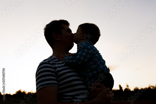 Father and his little son playing outdoors. Boy kisses his dad
