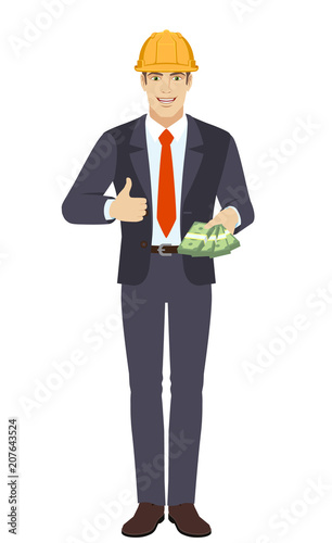 Businessman in construction helmet with cash mone showing thumb up