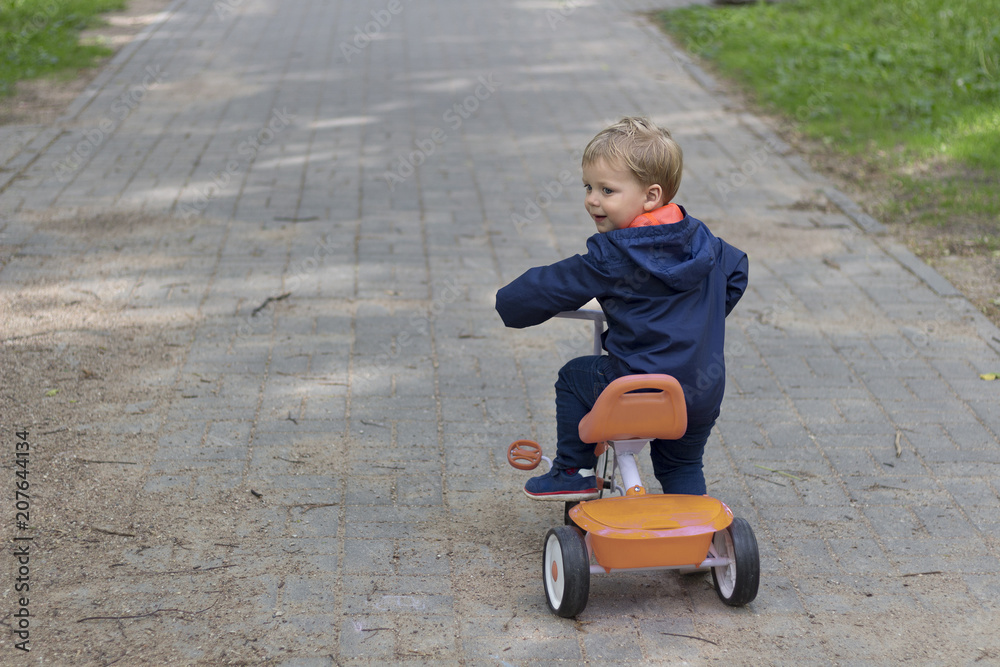 Child toddler playing riding a toy bike at a residential street with pavement.
