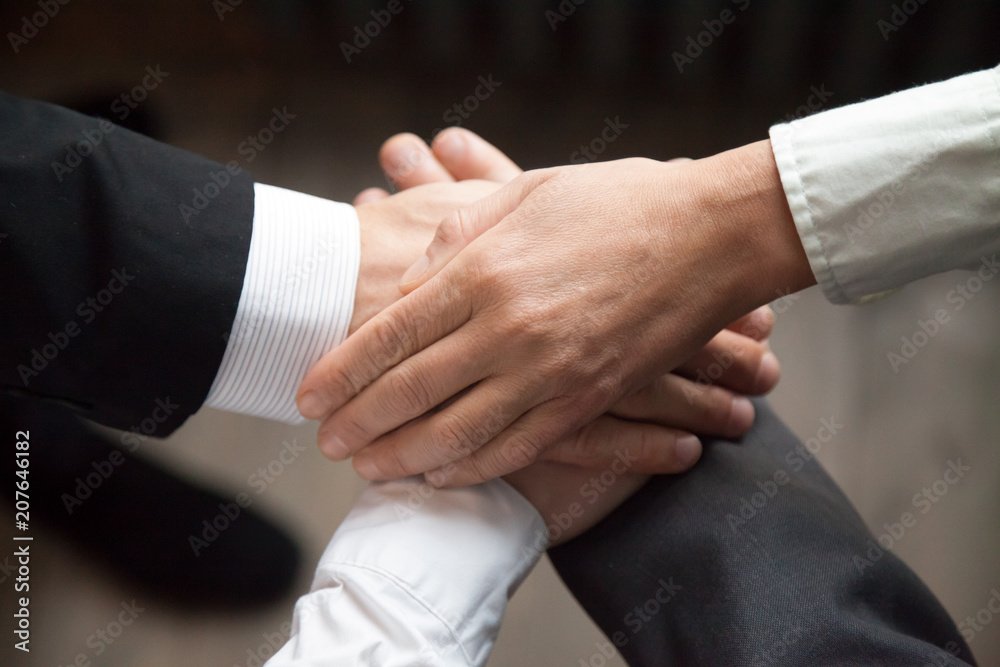 Close up of colleagues putting hands together, performing teambuilding activity during work office meeting, workers motivating aiming at support, goal achievement. Concept of unity, collaboration Close up of colleagues putting hands together, performing teambuilding activity during work office meeting, workers motivating aiming at support, goal achievement. Concept of unity, collaboration