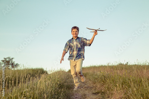 boy running with his airplane at green field