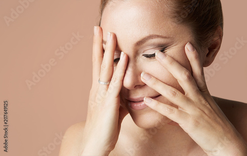 Young attractive girl with blonde hair fixed behind, closed eyes, thick eyebrows and naked shoulders holding hand near face at color background.Closeup portrait, copy paste space