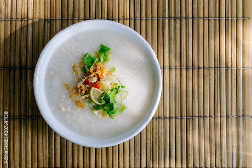 Thai style rice congee or rice porridge with ingredient condiments. (Fish sauce,fried garlic,chilli,pepper, spring onion, coriander and lime). photo