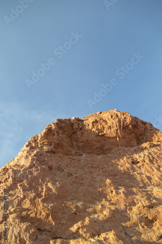 Uneven multicolored red, orange and yellow striped hills under a bright blue sky in Eastern Kazakhstan, vertical