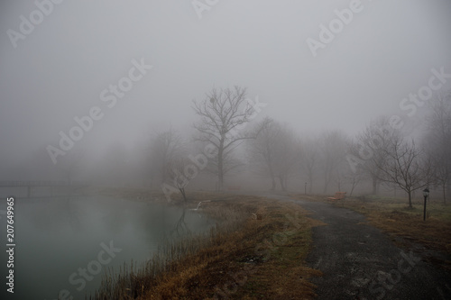 Amazing landscape of bridge reflect on surface water of lake, fog evaporate from pond make romantic scene or Beautiful bridge on lake with trees at fog.
