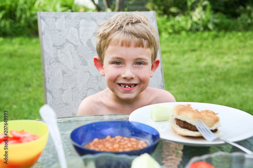 Smiling boy eating dinner outside, with a very loose front tooth,