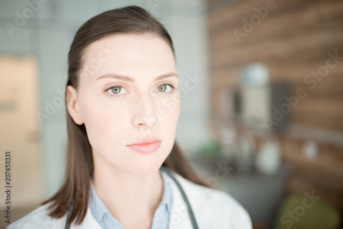 Young female in medical uniform looking at you during work in her clinics