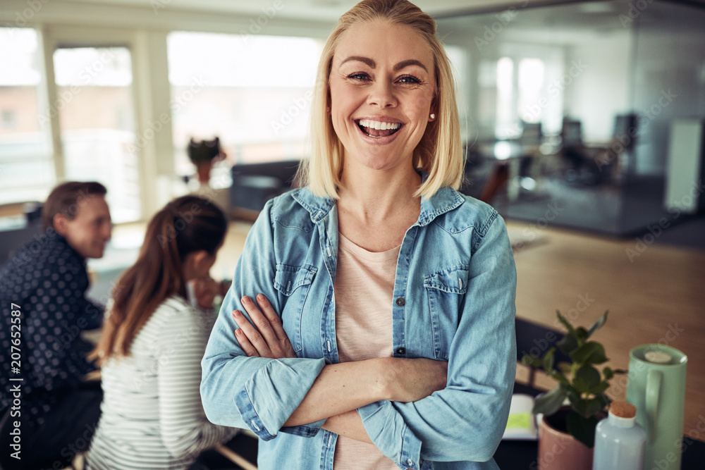 Laughing young businesswoman with colleagues working in the back Laughing young businesswoman with colleagues working in the back