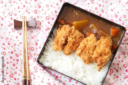Top view Japanese curry rice topping with fried chicken and vegetables in black plate with chopsticks. Curry rice Japanese food.