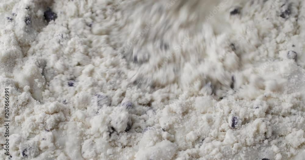 Close video of stirring milk into dry blueberry muffin mix with a white spoon. Close video of stirring milk into dry blueberry muffin mix with a white spoon.