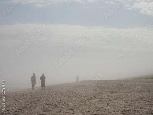 Para starszych ludzi spogląda na młodą parę we mgle na plaży.
