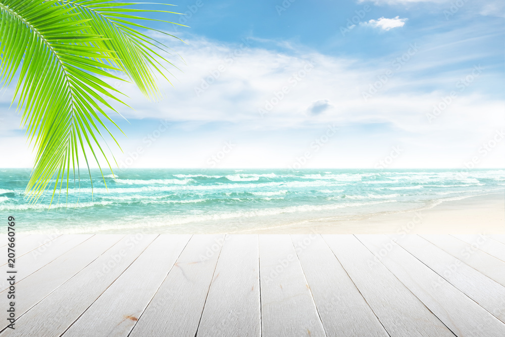 Fototapeta premium Empty wooden table and palm leaves with party on beach blurred background in summer time.