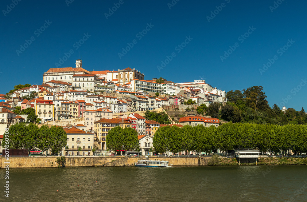View of Coimbra, in Portugal, on a sunny day, with Mondego River on the foreground.
