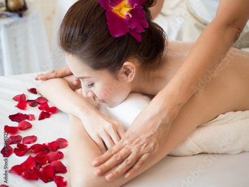 Young woman receiving back massage at spa salon.