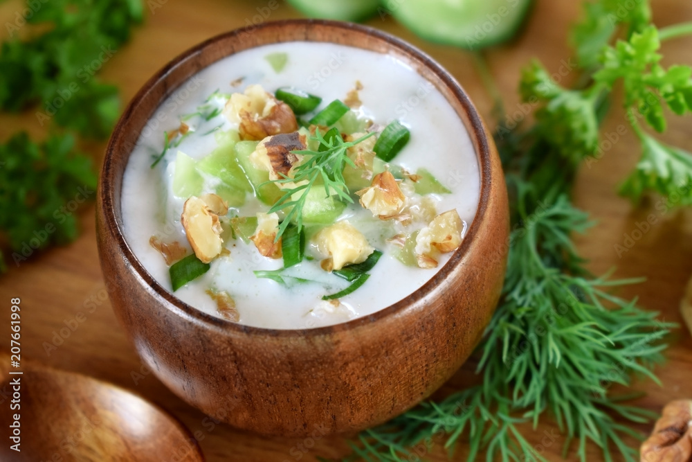 Cold soup Tarator with kefir in a wooden bowl. Bulgarian cuisine meal