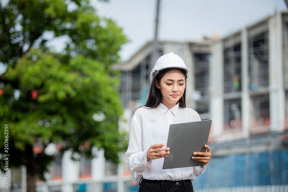 Female engineer inspecting construction work in hand holding clipboard with document.