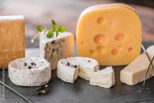 cheese board selection on old wood background emental, parmesan, swiss, creamy white mould, camembert brie castelo. blue mould stilton 