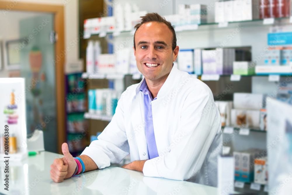 Happy adult man pharmacist in pharmacy giving a thumbs up gesture and smiling